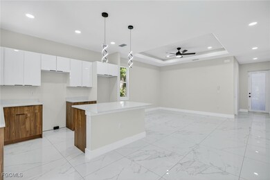 Kitchen with a tray ceiling, brown cabinetry, light marble finish floors, white cabinetry, and modern cabinets