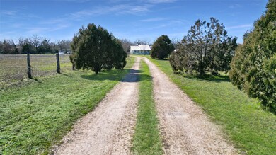 A dirt gravel road lined with trees takes you up t