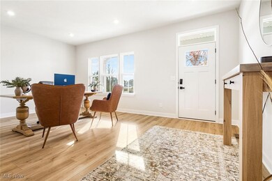 Home office with light wood finished floors and recessed lighting