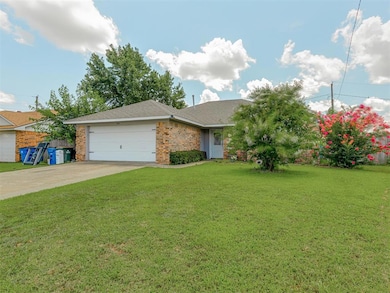 Single story home featuring a garage, driveway, a front yard, a shingled roof, and brick siding