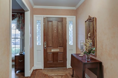 The gracious entry features a beautiful wood door, flanked by leaded glass sidelights, nice crown molding, and an attractive custom-patterned wood floor.  There are lovely hardwood floors throughout the original house.