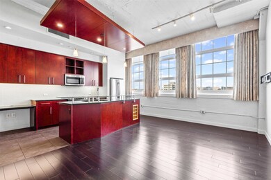 Kitchen featuring tasteful backsplash, stainless steel appliances, open shelves, dark wood-style flooring, and a kitchen island with sink