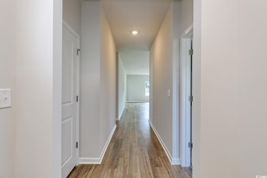 Corridor featuring light wood-type flooring, baseboards, and recessed lighting