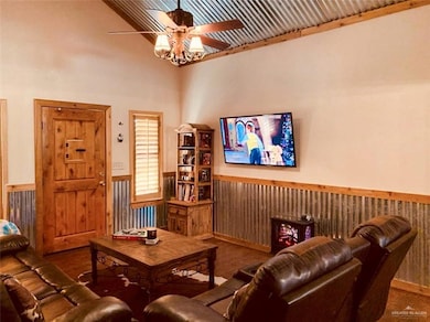 Living room with wainscoting, a ceiling fan, and a towering ceiling