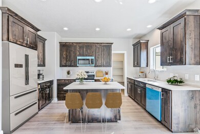 Kitchen with backsplash, stainless steel appliances, dark brown cabinetry, recessed lighting, and a kitchen island