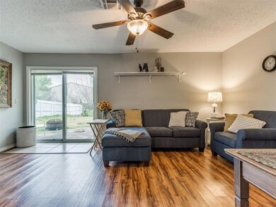 Living room with a textured ceiling, light wood-type flooring, and ceiling fan