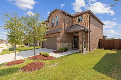 View of front of property with stone siding, driveway, brick siding, and an attached garage