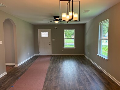 Entrance foyer featuring dark wood-type flooring, a ceiling fan, and arched walkways