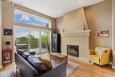 Living area featuring tons of natural light, wood floors, recessed lighting, a gas fireplace, and towering ceilings