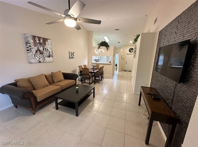 Living area with high vaulted ceiling, baseboards, light tile patterned flooring, visible vents, and a ceiling fan