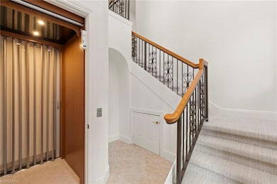 Staircase with elevator, arched walkways, and tile patterned flooring