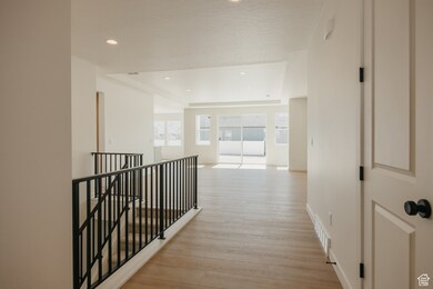 Hall featuring a tray ceiling, an upstairs landing, recessed lighting, and light wood-type flooring