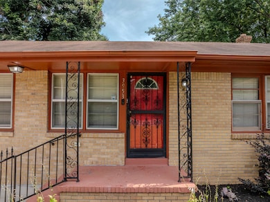 View of exterior entry with brick siding, roof with shingles, a chimney, and covered porch
