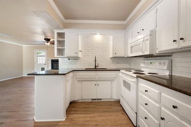 Kitchen featuring ornamental molding, white appliances, decorative backsplash, white cabinets, and light wood-style floors