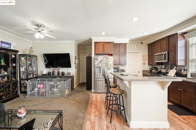 Kitchen with a kitchen bar, appliances with stainless steel finishes, ornamental molding, light stone counters, and recessed lighting