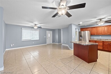 Kitchen with a center island, ceiling fan, stainless steel fridge, and light tile patterned floors