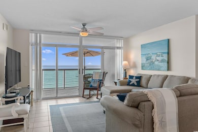 Living room featuring expansive windows, a water view, light tile patterned floors, and a ceiling fan