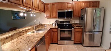 Kitchen with appliances with stainless steel finishes, a sink, oak  cabinetry, and granite stone counters