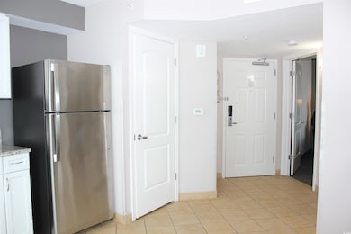Kitchen featuring stainless steel refrigerator, white cabinetry, and light tile patterned flooring
