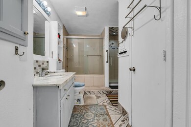 Bathroom featuring tile patterned floors, toilet, backsplash, vanity, and an enclosed shower