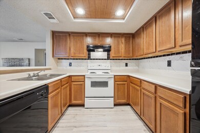 Kitchen with black dishwasher, white electric ran