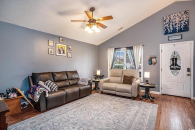 Living room featuring wood finished floors, vaulted ceiling, and ceiling fan