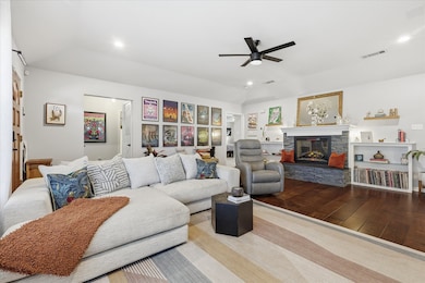 Living area featuring wood finished floors, a fireplace, ceiling fan, and recessed lighting