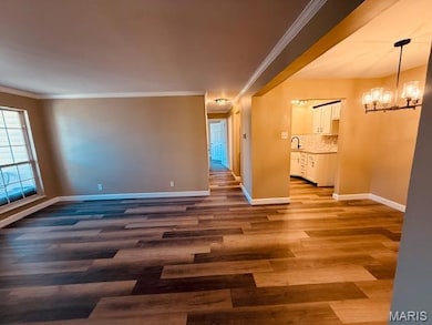 Unfurnished room featuring crown molding, a chandelier, and dark wood-style floors
