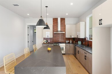 Kitchen featuring light wood-style floors, hanging light fixtures, tasteful backsplash, modern cabinets, and wall chimney range hood