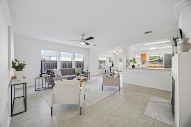 Living area featuring a fireplace, a ceiling fan, and light tile patterned flooring