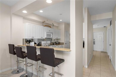 Kitchen featuring light tile patterned flooring, white appliances, sink, white cabinetry, and kitchen peninsula