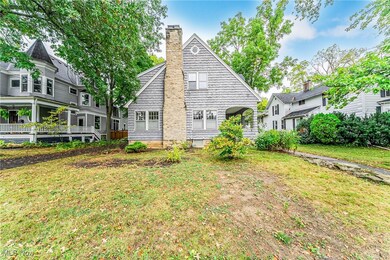 New England style home featuring a stone chimney, shingled siding, covered porch, and front yard