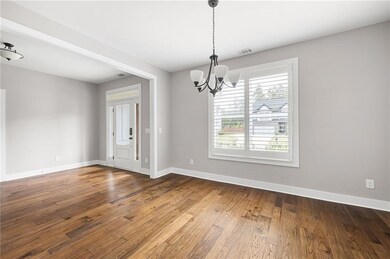 Unfurnished living room featuring a chandelier, high vaulted ceiling, dark wood-type flooring, a stone fireplace, and healthy amount of natural light