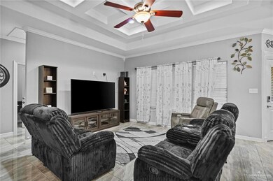 Living room with a ceiling fan, crown molding, marble finish flooring, and coffered ceiling
