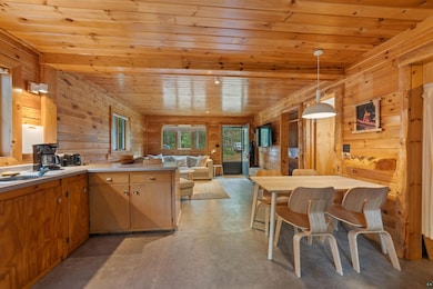 Kitchen featuring wood ceiling, finished concrete floors, open floor plan, wooden walls, and a peninsula