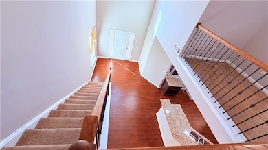 Staircase featuring wood finished floors and a high ceiling