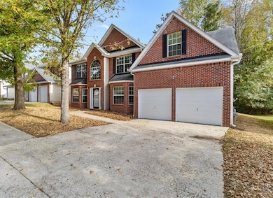 Traditional home featuring driveway, brick siding, and a garage