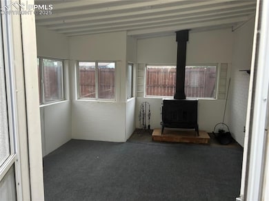 Unfurnished sunroom with a wood stove and beam ceiling