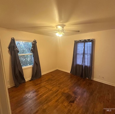 Empty room with dark wood-type flooring and baseboards
