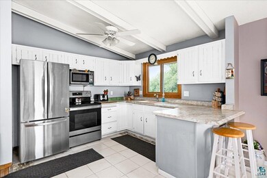 Kitchen with ceiling fan, vaulted ceiling with bea