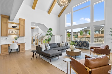 Living area with beam ceiling, light wood finished floors, a desk, a chandelier, and high vaulted ceiling