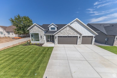 View of front of home featuring stone siding, board and batten siding, a front lawn, an attached garage, and concrete driveway
