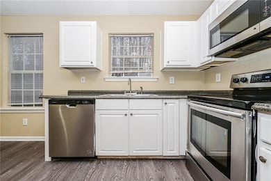 Kitchen featuring white cabinets, sink, appliances