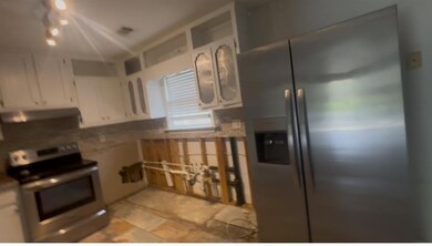 Kitchen featuring range hood, white cabinets, and 