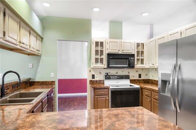 Kitchen with stainless steel fridge with ice dispenser, black microwave, electric range oven, a sink, and dark countertops