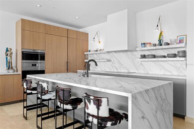 Kitchen has direct ocean views. Custom Neolith Calcatta Gold Matte finish countertops, backsplash, and island. Poliform open shelving and built in plaster finished hood. Custom matte black faucet. Sub-Zero 36