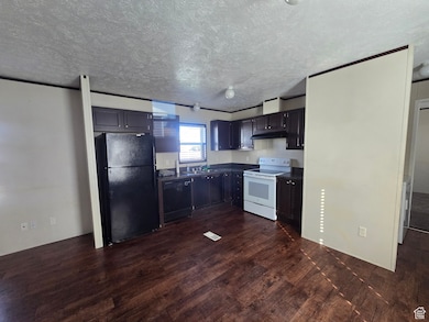 Kitchen with black appliances, dark countertops, dark wood-style floors, and a textured ceiling