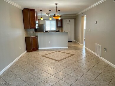 Kitchen featuring backsplash, light tile patterned floors, crown molding, brown cabinets, and hanging light fixtures