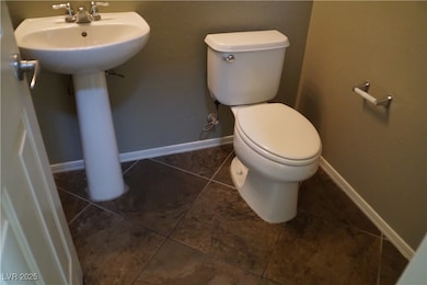 Half bathroom with toilet, a sink, tile patterned