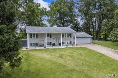 Bi-level home with concrete driveway, a chimney, and covered porch